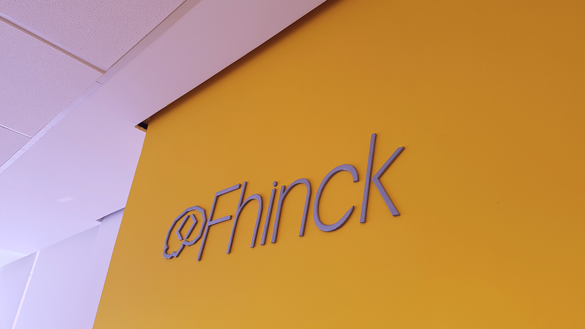 Logo da Fhinck na parede amarela